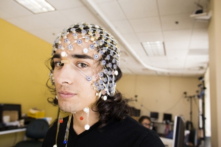 UCI doctoral candidate Sumner Norman wears an EEG cap that figures prominently in his robotics research to help stroke victims. Elena Zhukova / UCOP
