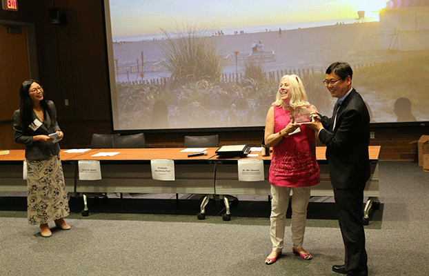 Professor Hee-Deung Park from Korea University presents Olson with a plaque while Jiang looks on.