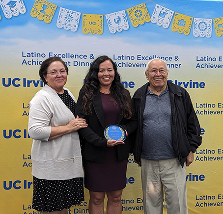 Michelle Digman (center, alongside her parents) accepts the Outstanding Faculty Mentorship Award at the 2024 Latino Excellence and Achievement Awards Dinner (LEAD).