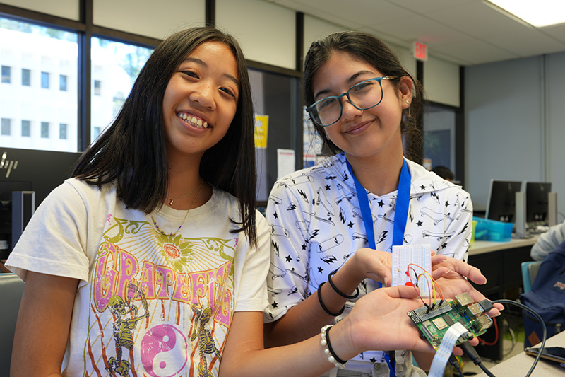 Tiffany Le, 13, and Ari Martino, 13, show off the Raspberry Pi they coded to create a photo booth at FABcamp. (Photo: Natalie Tso/UCI)
