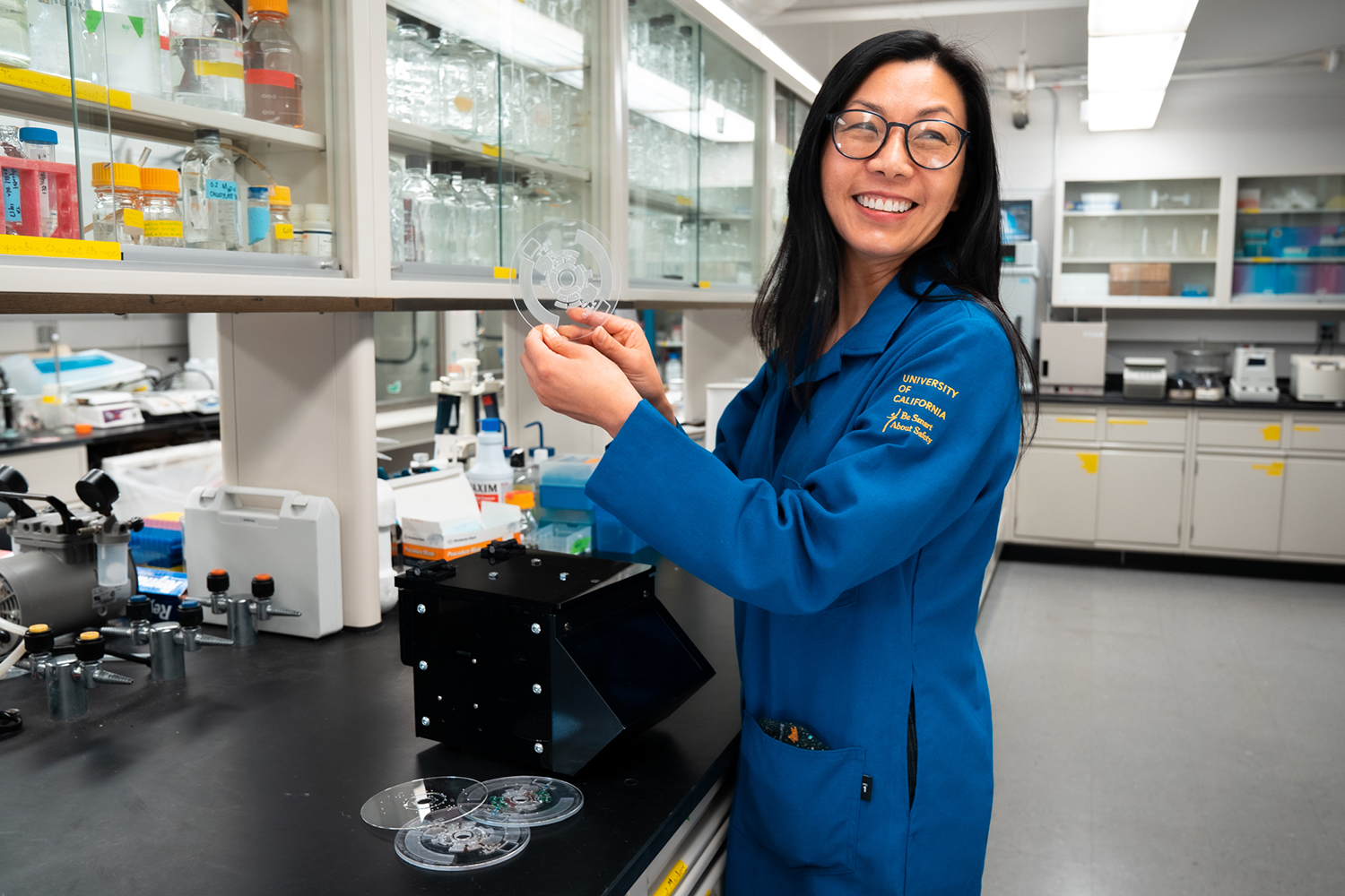UCI Professor Sunny Jiang adds a uniquely created microfluidic disc to her portable pathogen analysis system prototype in her lab located at UCI's Henry Samueli School of Engineering.