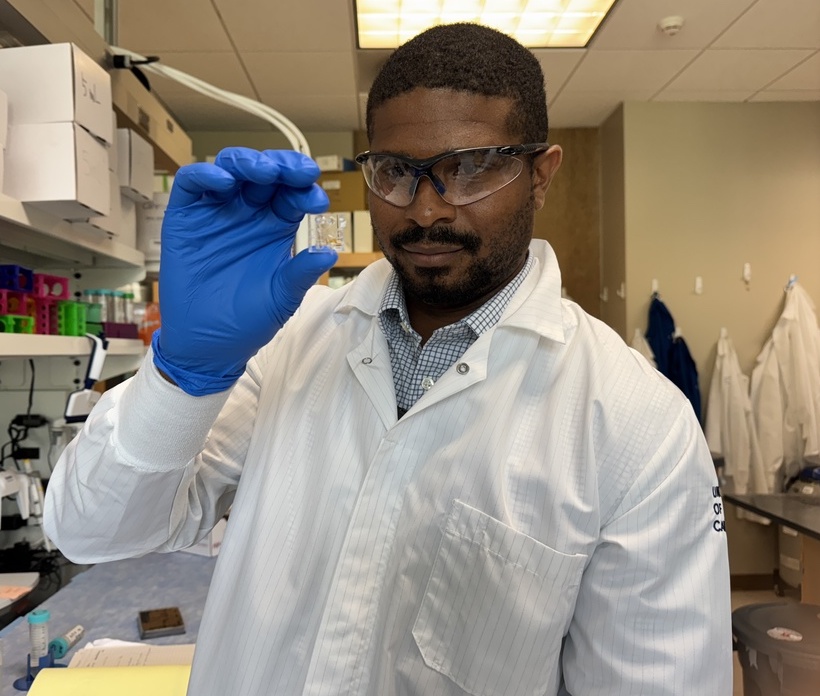 UCI assistant professor of chemical and biomolecular engineering Quinton Smith holds up a chip where his lab grows organoids. (Photo: Natalie Tso/UCI)