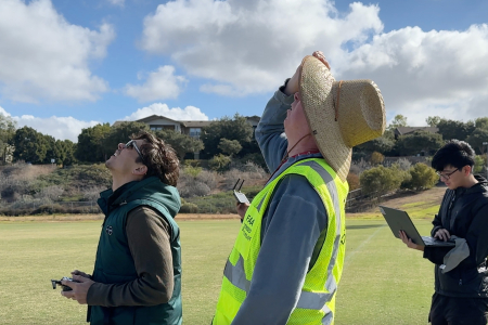 From left: Computer science engineering senior Aiden Dodge, Professor Peter Burke and teaching assistant Patrick Rwei watch Dodge’s drone fly.