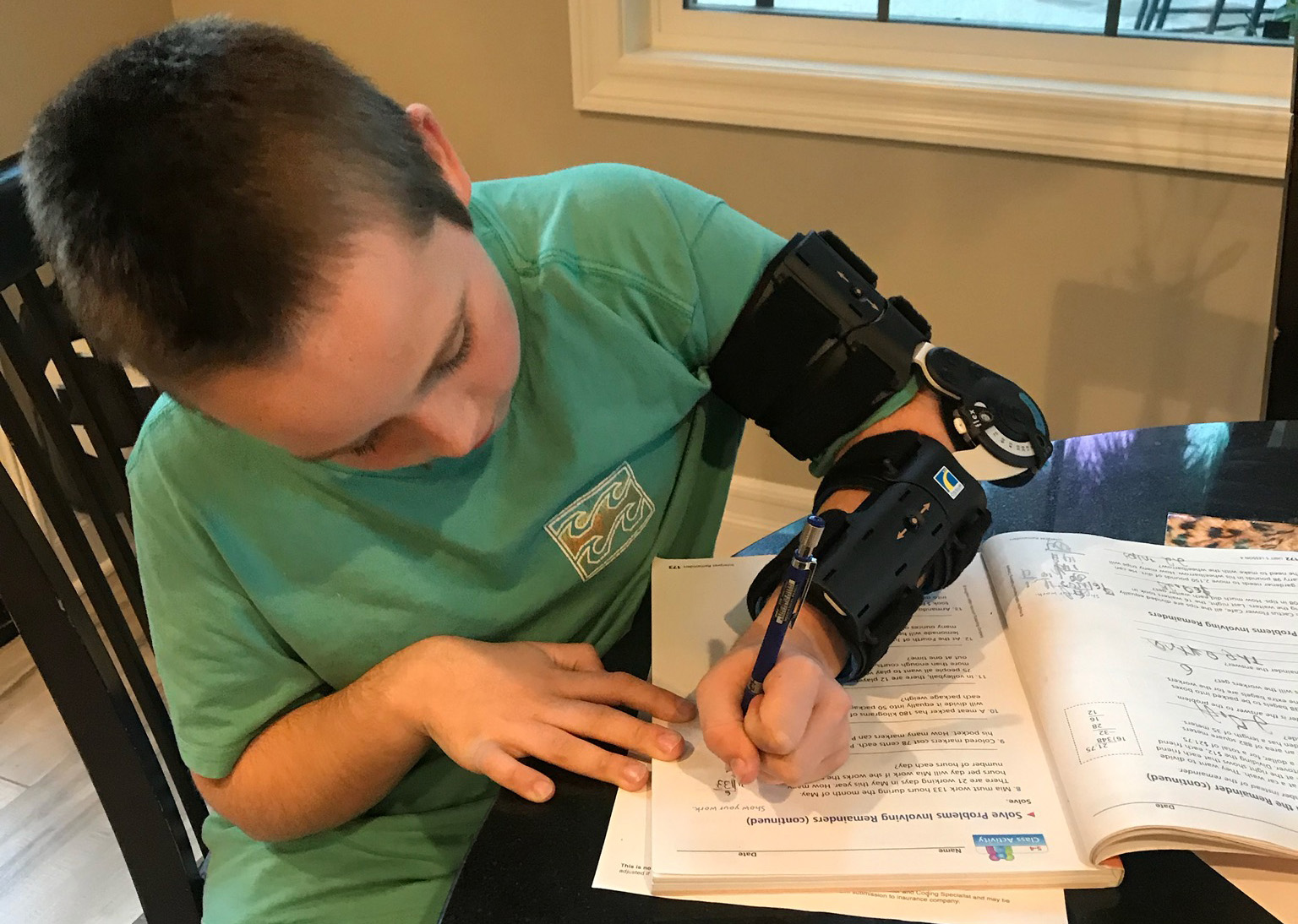 Dylan Law writing at a normal pace with an early prototype of the Move-D brace